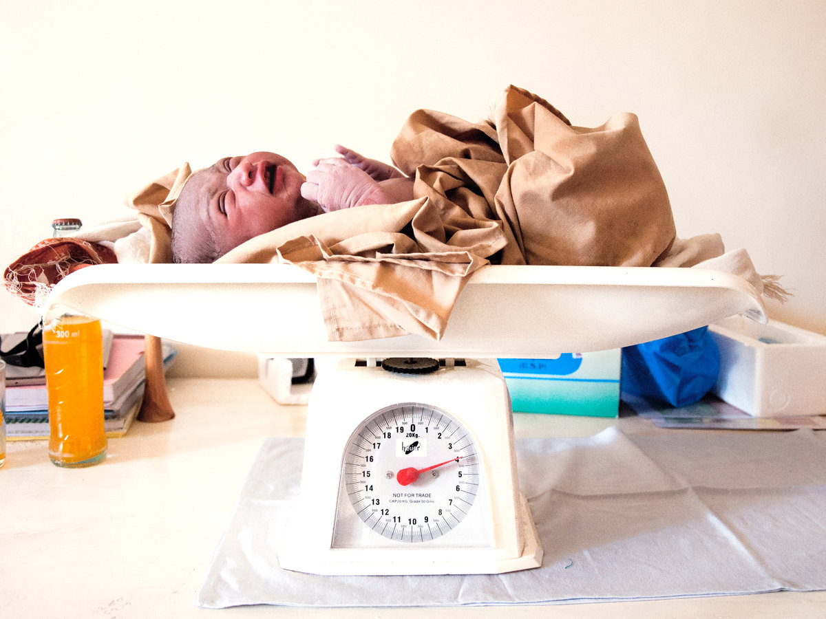 Health centre staff weighing and checking a baby